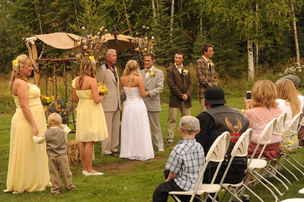 Outdoor country wedding ceremony with bridesmaids and groomsmen